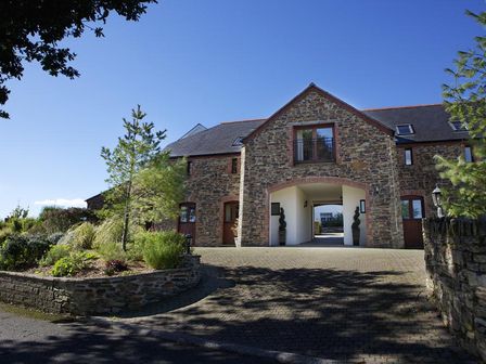 A stone building with an archway and plants outside at 2 New Barn Hillfield Village in Dartmouth