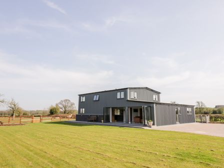 A modern two-story house with large windows and a green lawn at Phoenix House in Castlemorton