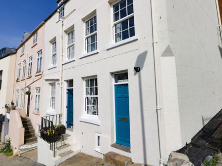 The exterior of a white building with blue doors and multiple windows on a street at Hooks House in Scarborough
