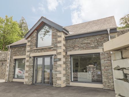 Stone house exterior with large glass windows and double doors at Lower Lake View in Bowness-On-Windermere