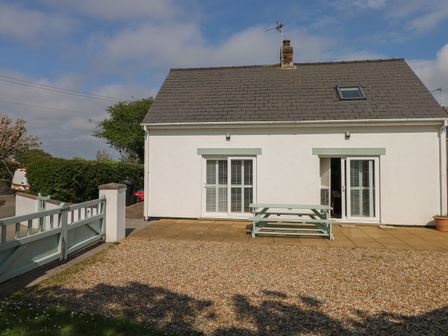 A white house with two glass doors a picnic table and gated driveway at Yr Hen Ardd in Dale near Milford Haven