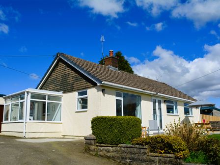 A single-story house with a conservatory and garden furniture at Gwynant in Pontrhydfendigaid