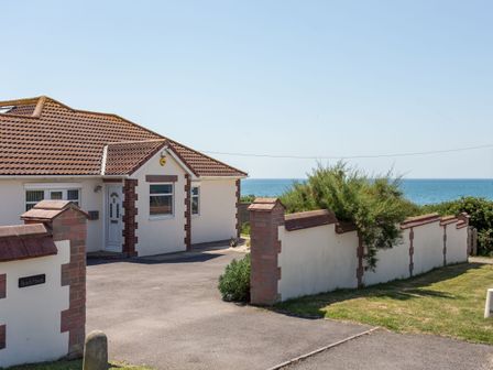 A single-story house with a tiled roof and a paved driveway near the ocean at Beach Haven in West Bexington