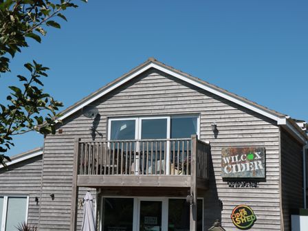A wooden building with a balcony and signs reading Wilcox Cider and The Cider Shed in Winscombe