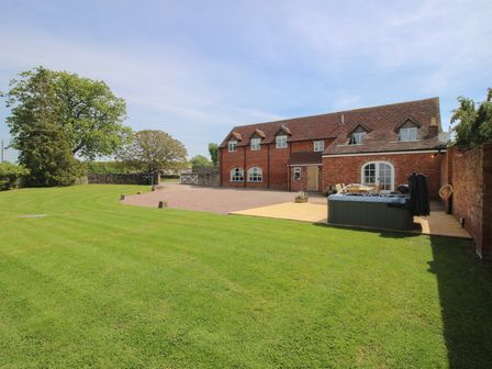 A house with a lawn and hot tub at Hunters Moon in Tenbury Wells