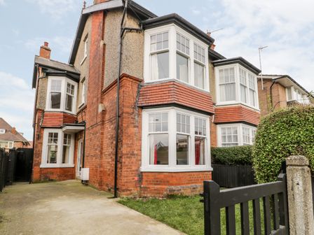 A two story brick house with white framed bay windows and a black gate at Beach House in Bridlington