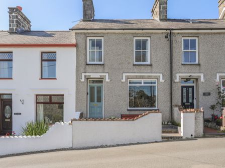 A row of terraced houses with pebble dash and white walls and small front gardens at Maes-Yr-Haf in Criccieth