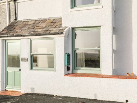 White exterior wall with green door and windows and a green mailbox at Ty ar Ben Bryn in Pencarnisiog near Rhosneigr