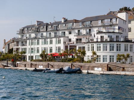 A waterfront building with balconies palm trees and boats docked at 37 The Salcombe in Salcombe