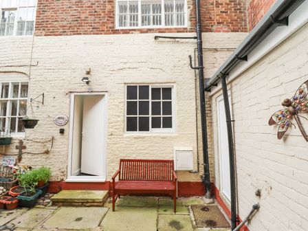 A courtyard with a red bench in front of a cream brick wall at Station View in Whitby
