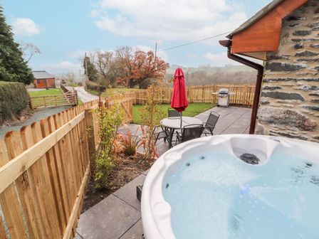 A garden with a hot tub and seating area at Cut Moch, Plas Moelfre Hall Barns Moelfre near Llanrhaeadr-Ym-Mochnant