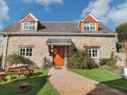A stone house with a wooden door and two dormer windows and a garden path at The Linhay in Chardstock