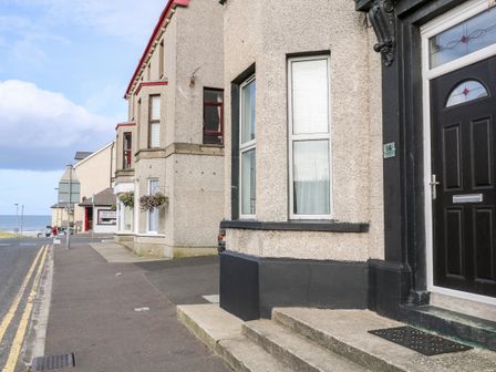 A street view with stone houses and a black door near the sea at Beachside and Golf Apartment in Castlerock