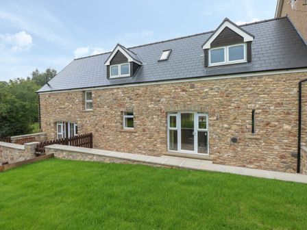 Stone exterior wall of a house with two dormer windows and a lawn in front at Woodpecker Barn in Hensol near Pontyclun