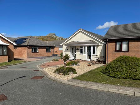 A street view of single story houses with driveways and a small garden at Seagull Cottage in Trearddur Bay