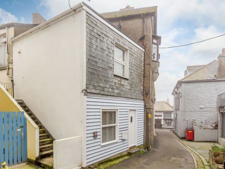 A narrow street with houses and mossy stairs and a blue gate at The Boat House in Looe