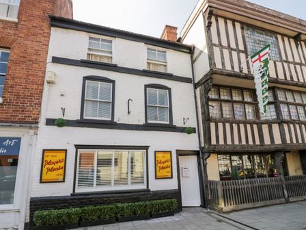 A street view with a white and black building and a timber framed building with a flag at The Old Paper Shop in Tewkesbury