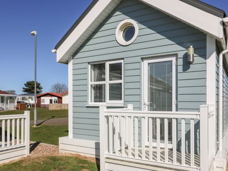 Exterior of a small blue house with white door and window and a white railing at Shore Thing 279 in Wilsthorpe