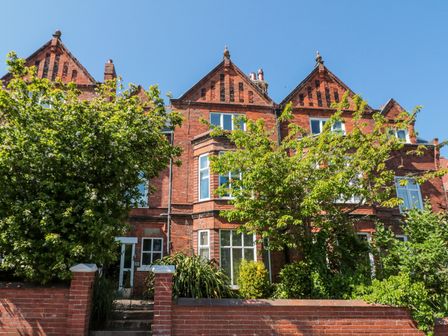 A red brick residential building with bay windows and trees in front at Royal Victoria House in Scarborough