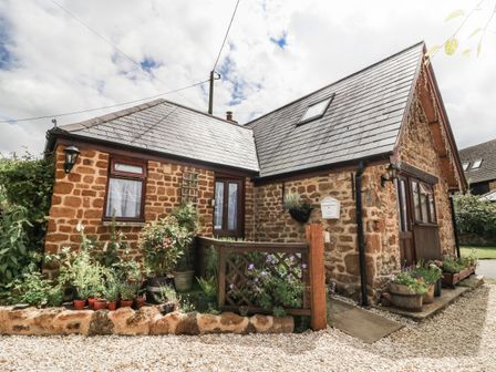 A stone cottage with a slate roof and garden pots at The Forge at Smithy Cottage in Bloxham