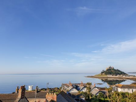 A coastal view of rooftops and a castle on a hill by the sea at Ocean View in Marazion