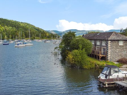 A body of water with sailboats and a stone building by the shore at Gilson in Far Sawrey