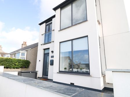 Exterior view of a two-story white house with large windows and a dark front door at Arlanfor in Rhosneigr