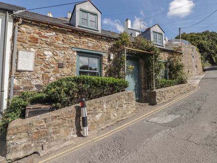 A stone cottage with blue framed windows and door alongside a narrow road at Patty's Cottage Little Haven near Broad Haven