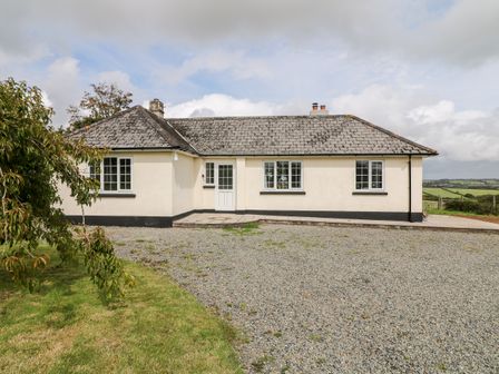 A single story house with a gravel driveway and grass lawn at Summercourt in Tremaine