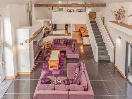 An open living area with purple sofas and a wooden coffee table with a glass top at Flint Barn in Knapton