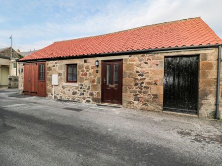 A stone building with a red tile roof and multiple wooden doors and windows at The Old Stables in Belford