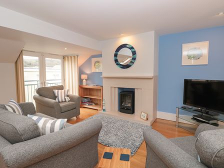 A living room with grey armchairs and sofa a fireplace and a television at 42 Dart Marina Dartmouth