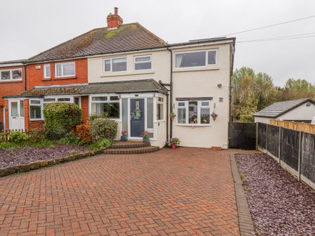 A semi detached house with a brick driveway and garden beds at Castle View in Burniston