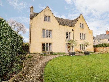 A large yellow house with multiple windows and a gravel pathway leading to the entrance surrounded by a lawn at Chapel House in Leonard Stanley near Kings Stanley