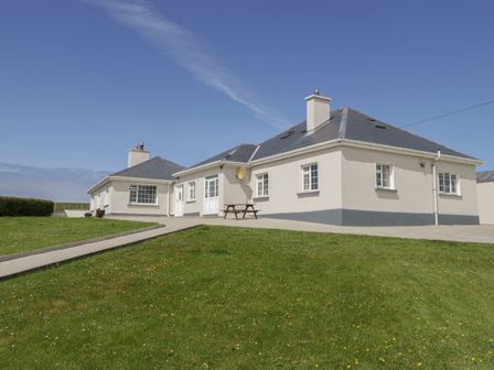 A single story house with a gray roof and white walls surrounded by a lawn at Erris Head House in Glenlara near Belmullet County Mayo