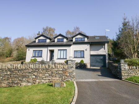 A white house with three dormer windows stone walls and a driveway at Bishop Fell in Newby Bridge