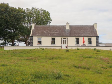A single story house with a slate roof and white walls on a grassy field at Newtown East near Kilkee County Clare