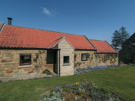 A stone cottage with a red tiled roof and garden flowers at Silver Birches in Glaisdale