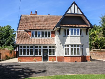 A two-story house with a tiled roof and multiple windows with white frames and blinds at Greenlawns in Burnham-On-Sea