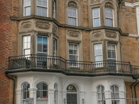 Exterior view of a multi-story building with bay windows and a black metal balcony at a property named Millworth House