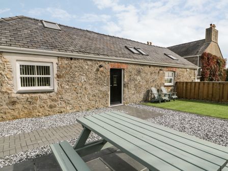 An outdoor area with picnic table, two armchairs, stone building with windows and door at 1 Mountain View Talwrn near Llangefni