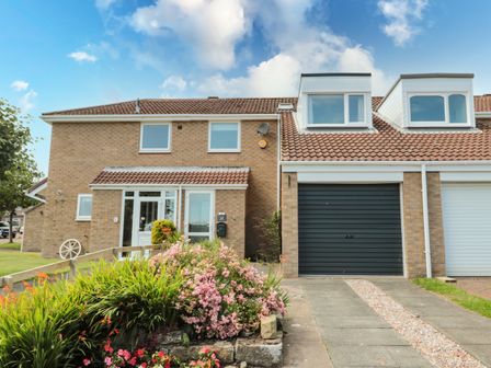 A two-story brick house with a garden and driveway in front at Tearlach House Alnwick