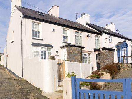 A row of white houses with stone accents and blue gates at Old Post Office in Bull Bay