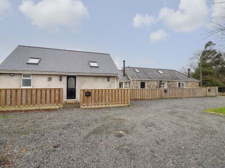 A gravel driveway leading to two adjoining houses with wooden fences in front at 3 Mountain View in Talwrn near Llangefni