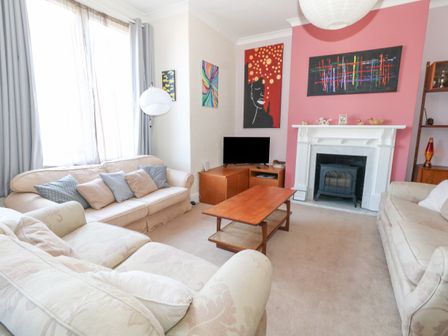 A living room with sofas a coffee table a fireplace a television and wall art at Victorian Town House in Weymouth