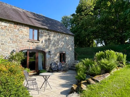 A stone cottage with a patio table and chairs and plants outside at Stable Cottage in Newport Pembrokeshire