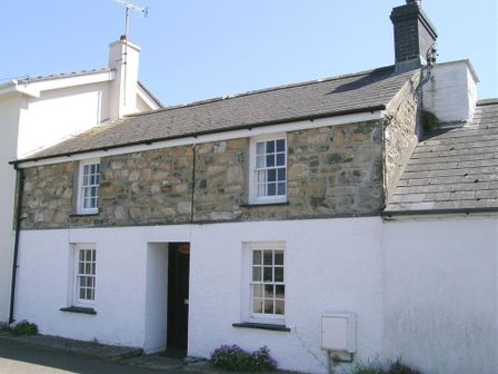 A stone and white exterior cottage with four windows and a chimney at Derlwyn in Newport Pembrokeshire