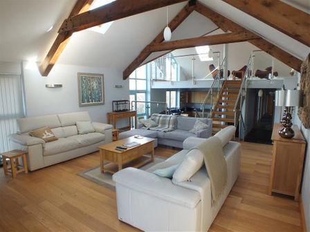 An open living room with sofas coffee table wooden beams and stairs at Seabrook Broad Haven Pembrokeshire