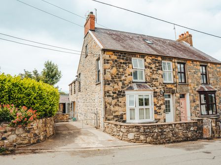 A stone house with a driveway and green hedge at Lyndale in Newport Pembrokeshire
