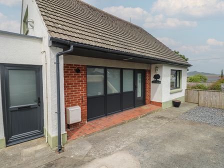 The exterior of a house with a tiled roof a gray door large windows and a driveway at Greenfields in St Davids Pembrokeshire